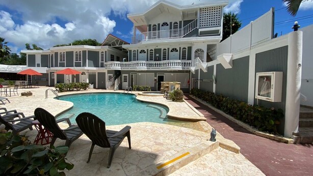 A resort with a swimming pool, outdoor seating, and a two-story building with balconies. - The Village Inn Hotel (Carolina)