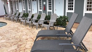 A row of chairs and a pool area with a stone floor. - The Village Inn Hotel (Carolina)