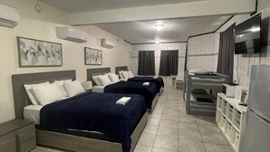A hotel room with three beds, a kitchenette, and a TV. - The Village Inn Hotel (Carolina)