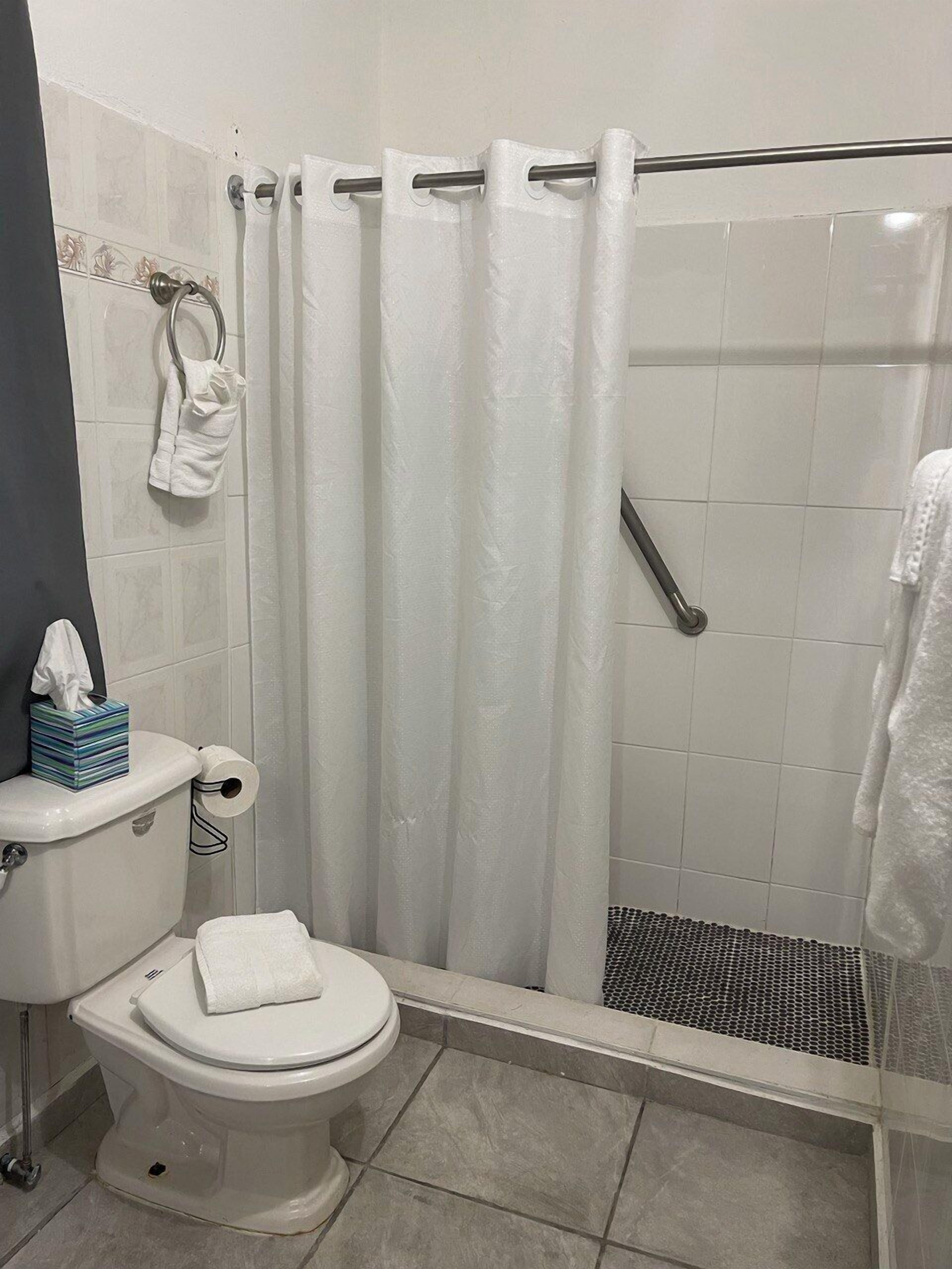 A bathroom with a toilet, a shower with a glass door, and a towel rack.
