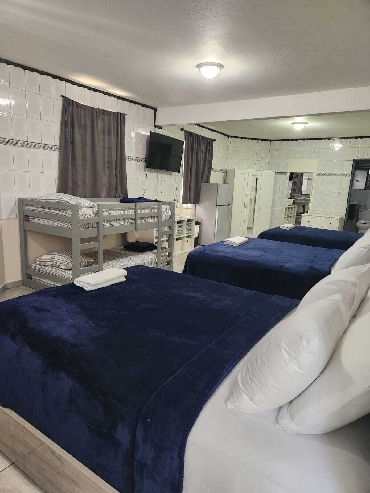A hotel room with two beds, a television, a mirror, and a kitchenette.