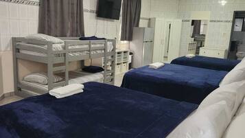A hotel room with two beds, a television, a mirror, and a kitchenette.