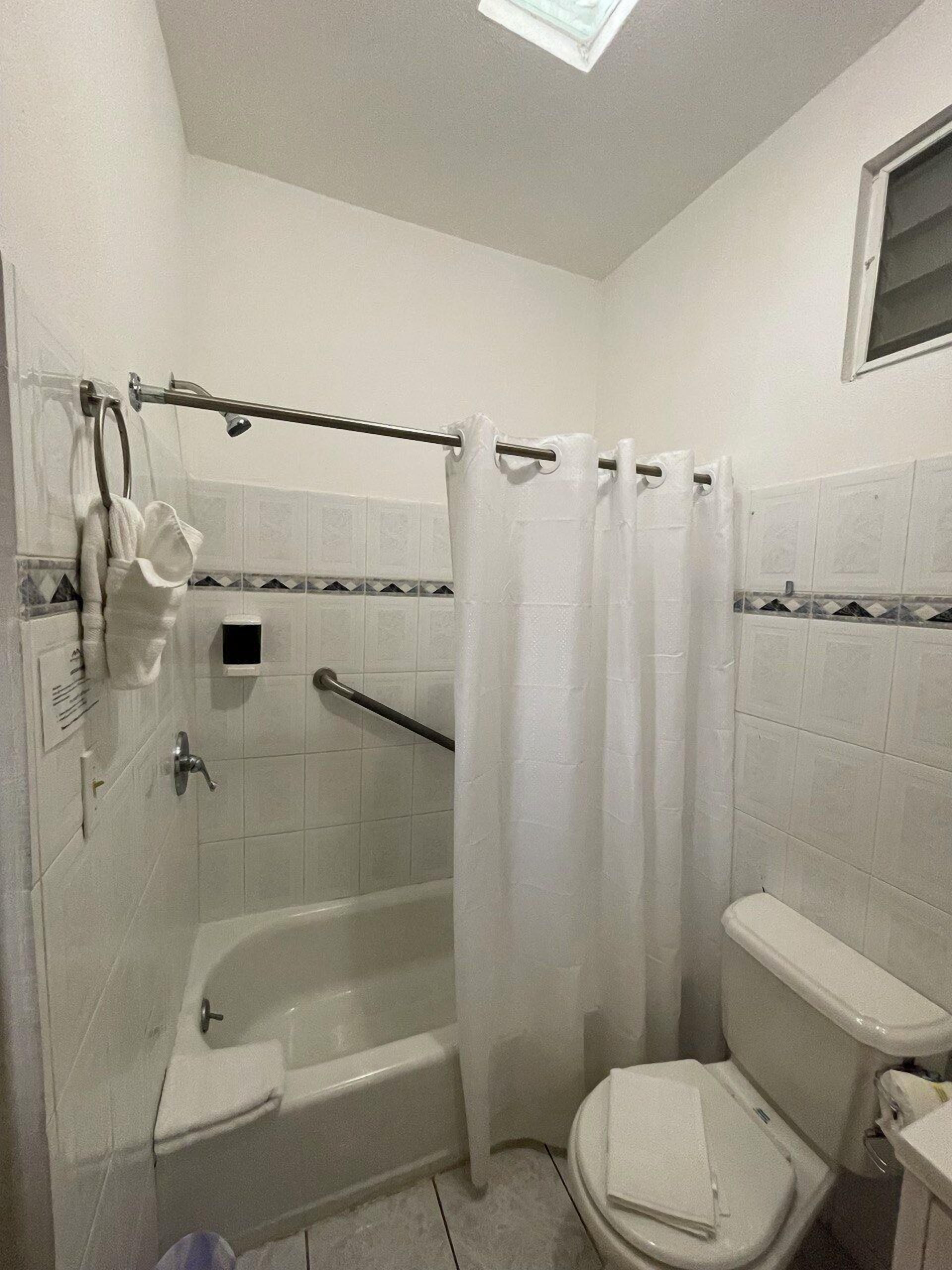 Un baño con bañera, inodoro y cortina de ducha.