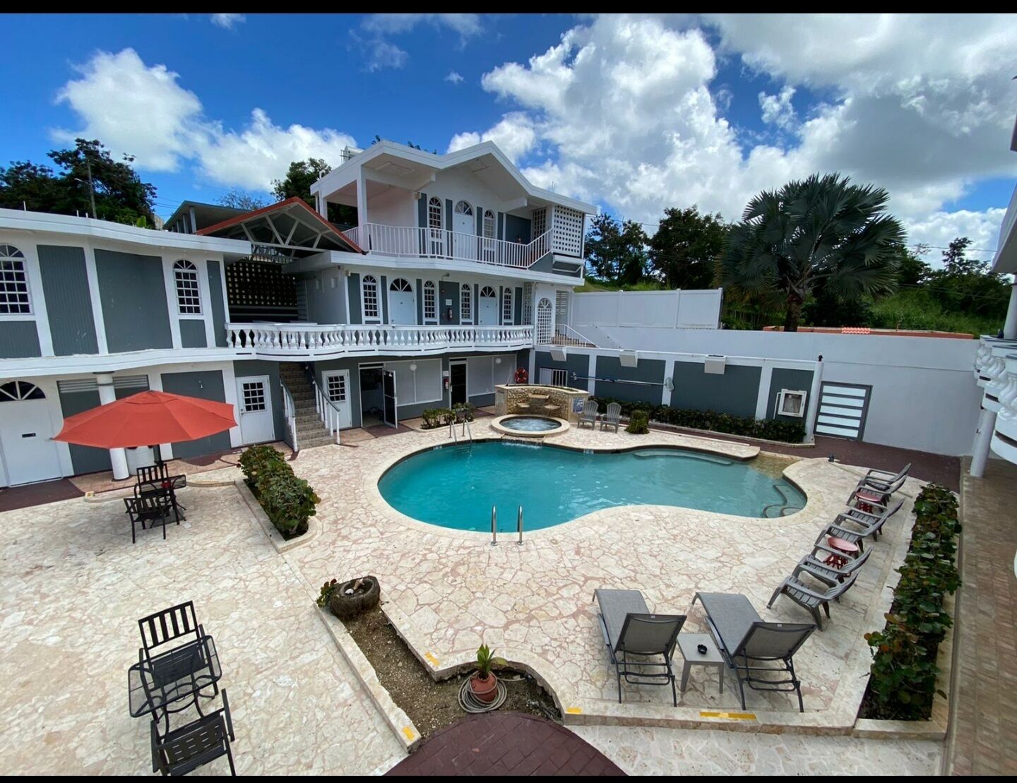 A two-story building with a swimming pool, outdoor seating, and a covered patio area.