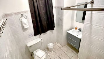 Een badkamer met toilet, bidet, wastafel en een douchegedeelte.