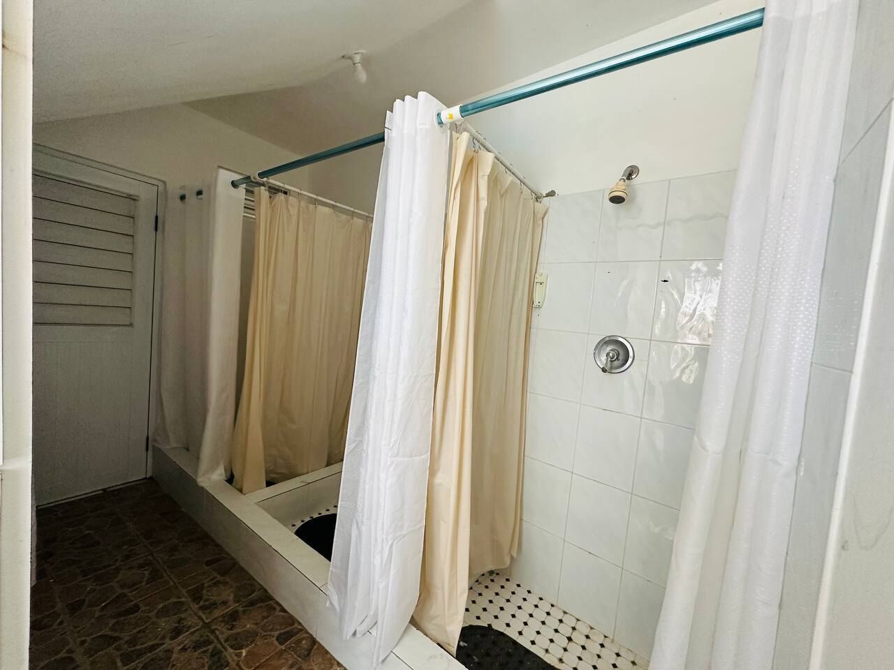 Un baño con ducha, paredes de azulejos y una puerta.