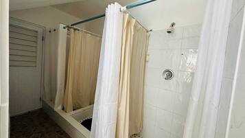 Un baño con ducha, paredes de azulejos y una puerta.