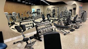 A gym with various exercise equipment, including dumbbells, treadmills, and weight machines.