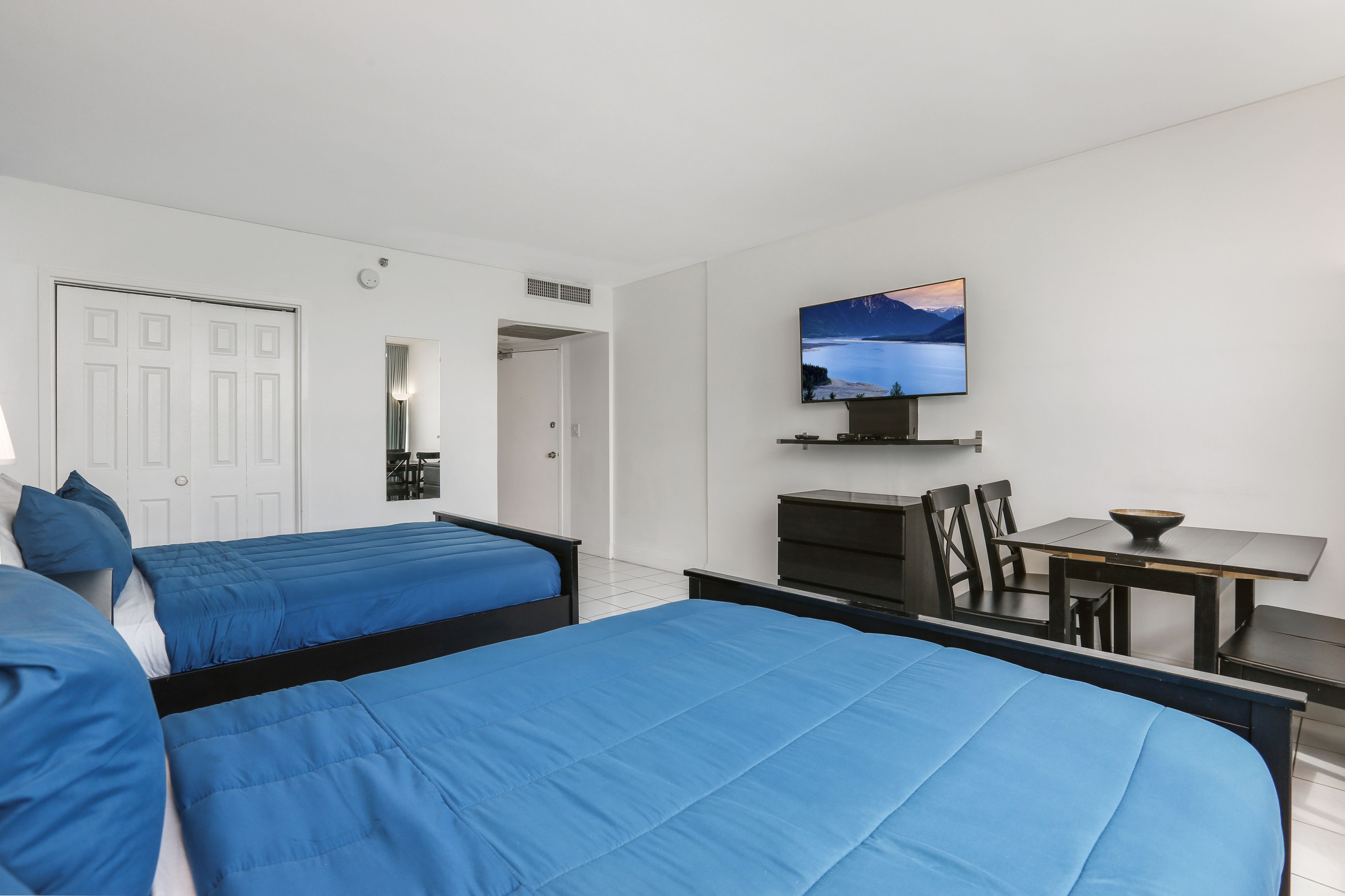 Ett hotellrum med två sängar, ett skrivbord, en stol, en tv och utsikt över en sjö.