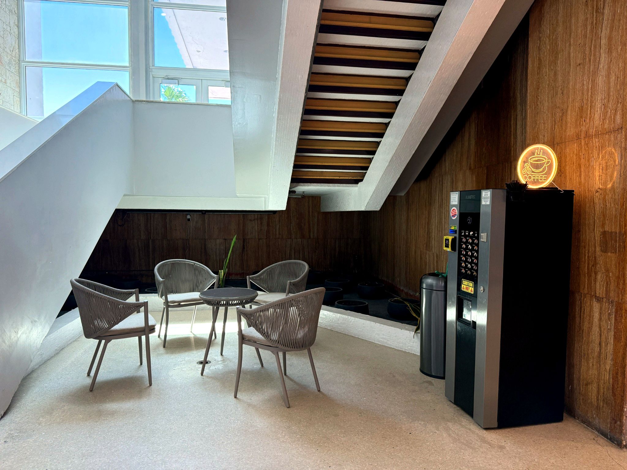 Un intérieur moderne comprenant un coin repas, une machine à café et un escalier.