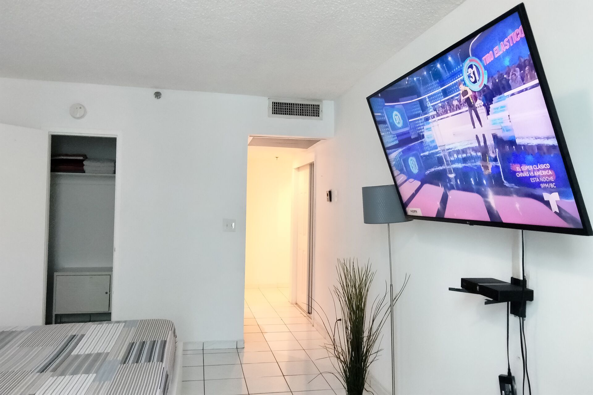 Una sala de estar moderna con un televisor de pantalla plana montado en la pared, un sofá y una planta en maceta.