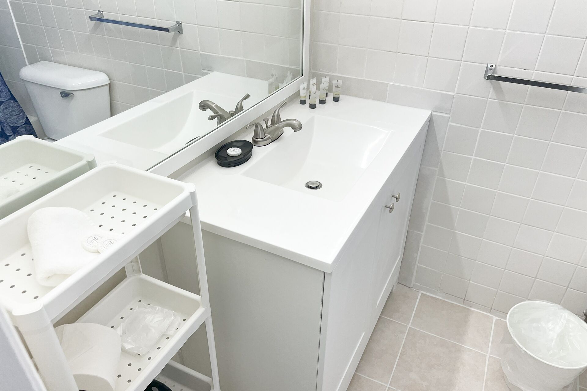A bathroom with a white sink, mirror, and two shelves with toiletries.