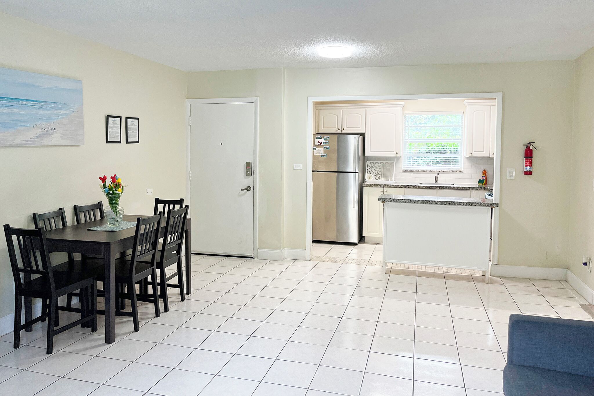 A compact kitchen with white cabinets, a stainless steel refrigerator, and a tiled floor.