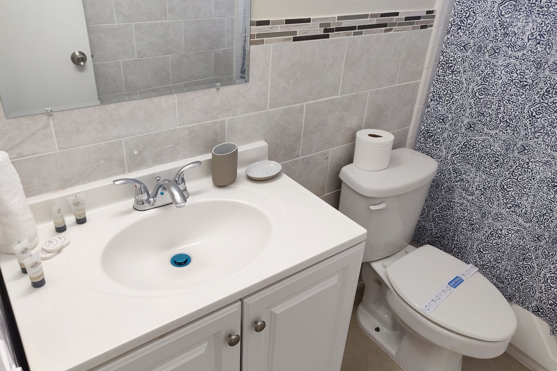 A bathroom with a white sink, a toilet, and a patterned shower curtain.