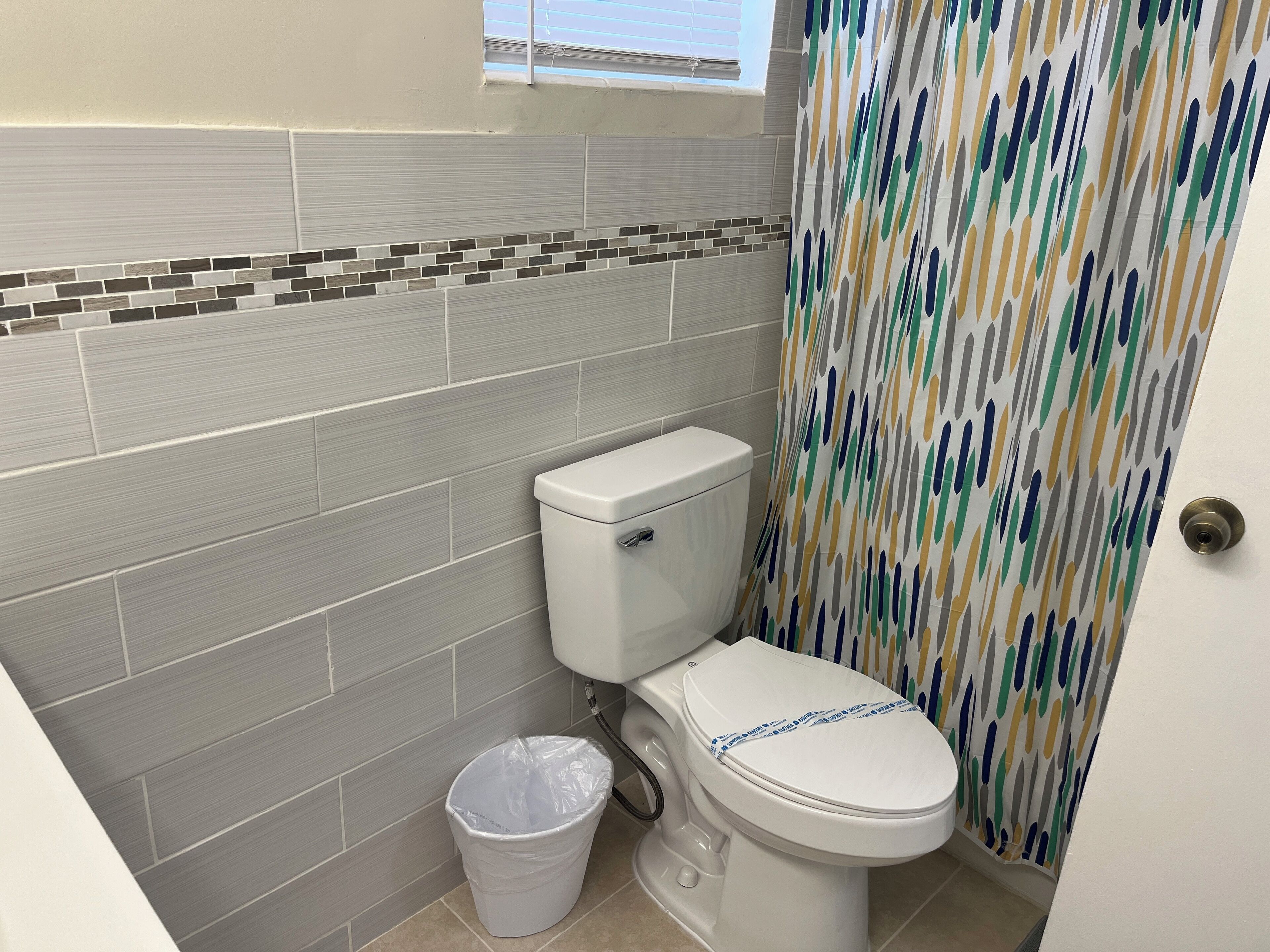 Ein Badezimmer mit Toilette, Mülleimer und Duschvorhang.