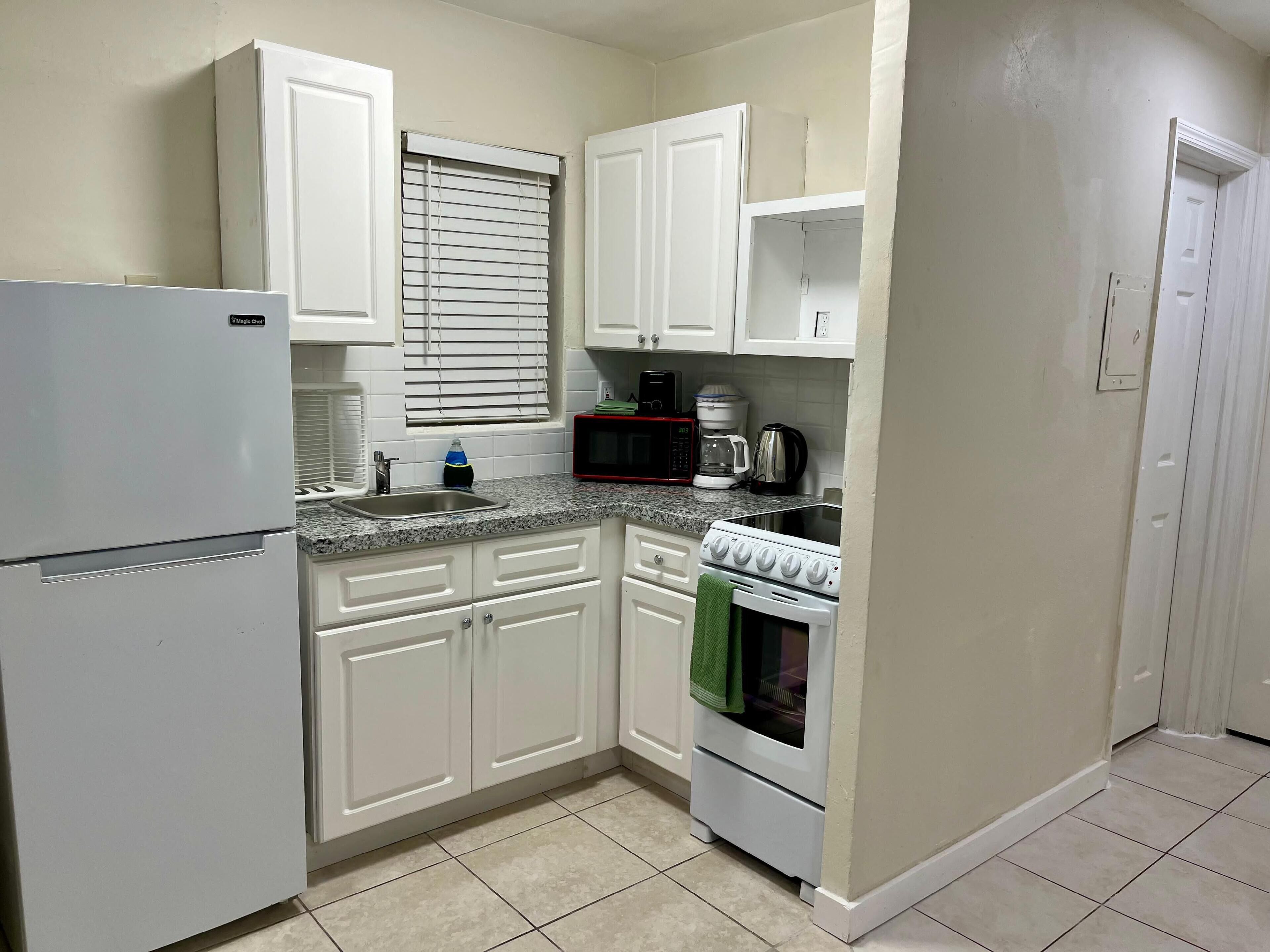 A compact kitchen with white cabinets, a built-in microwave, a stove, and a refrigerator.