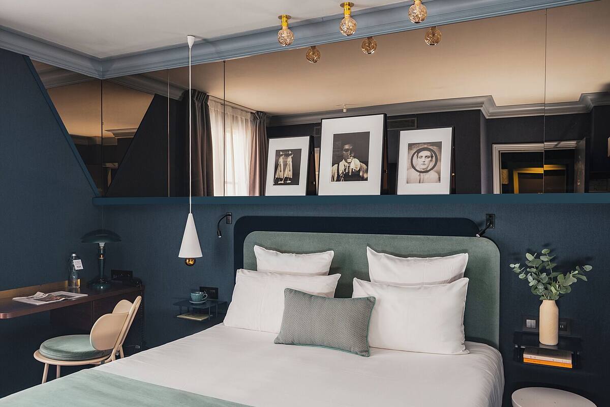 A modern bedroom with a large bed, a desk, and a mirror.