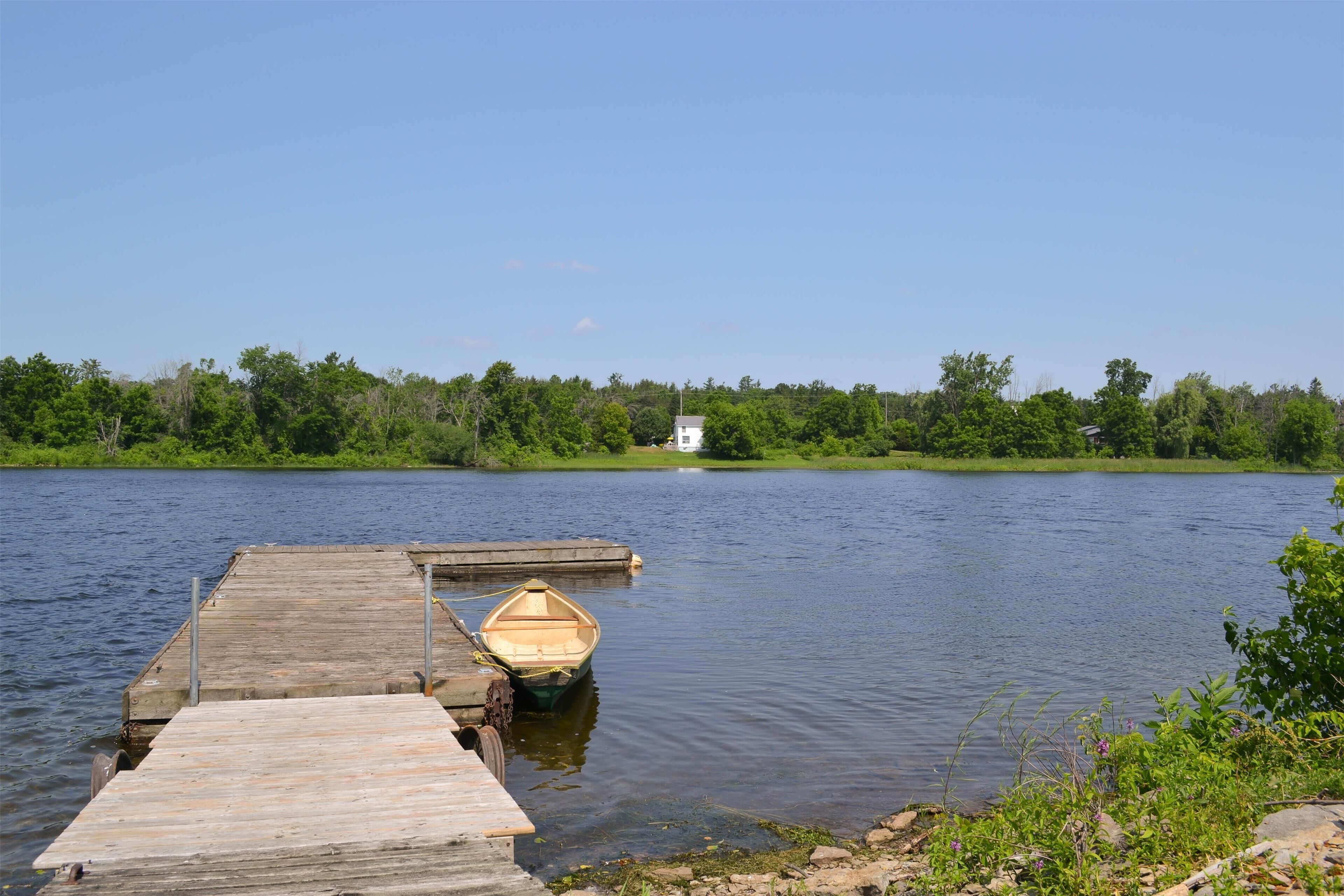 A wooden dock extending into a calm lake with a small boat tied to it.