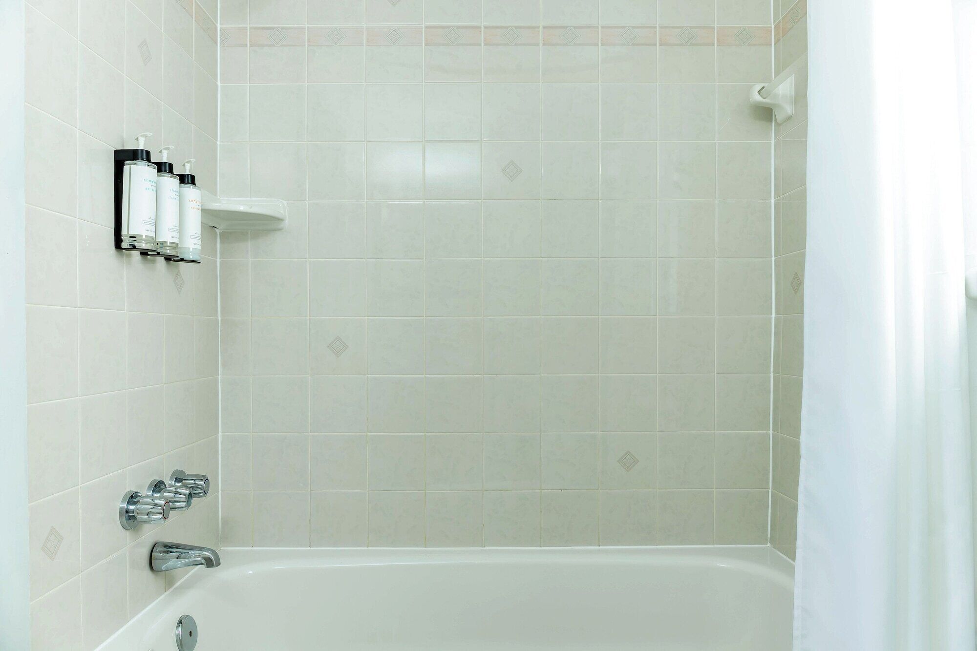 A bathroom with a bathtub, a shower, and a shelf with toiletries.
