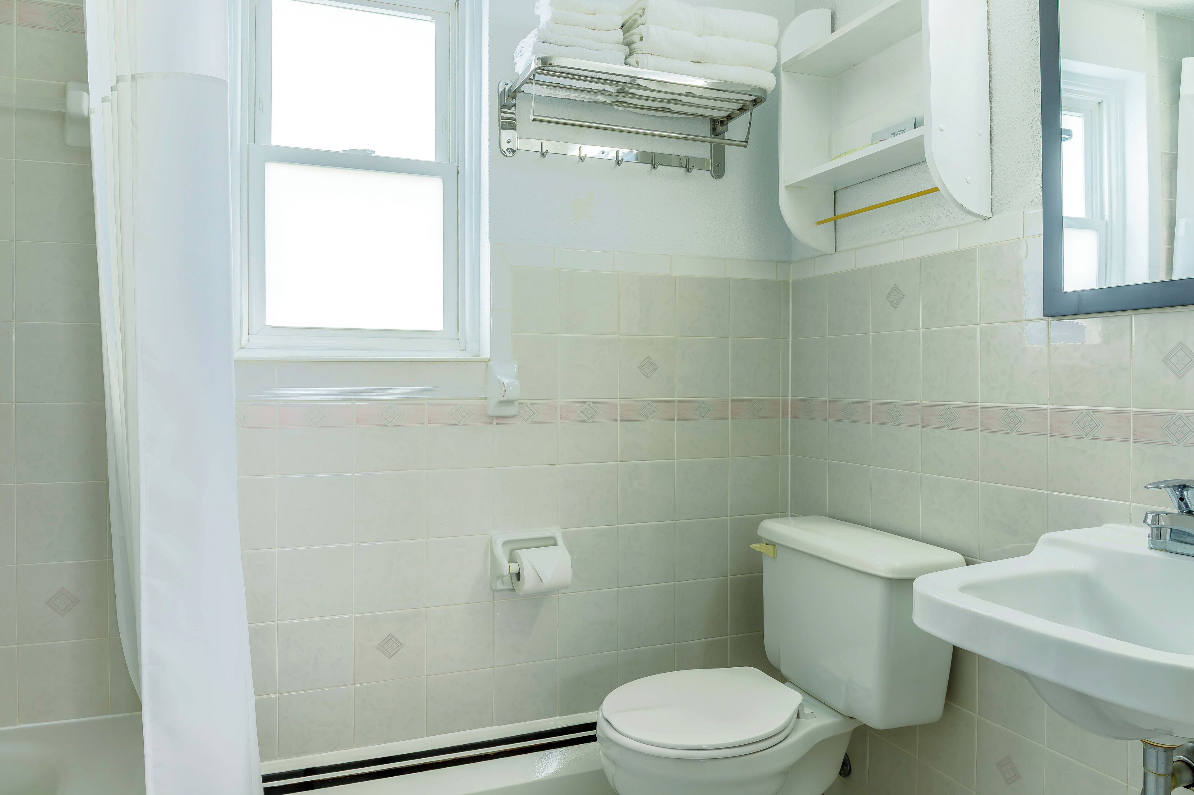 Une salle de bain comprenant des toilettes, un lavabo, un porte-serviettes et une fenêtre.