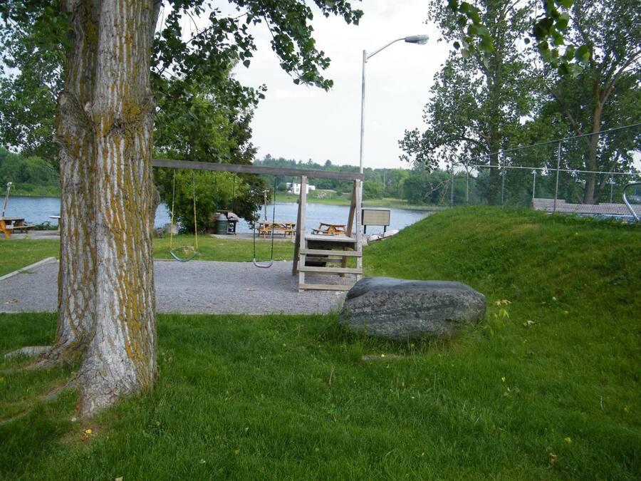 A park with a swing set, picnic tables, and a large rock.