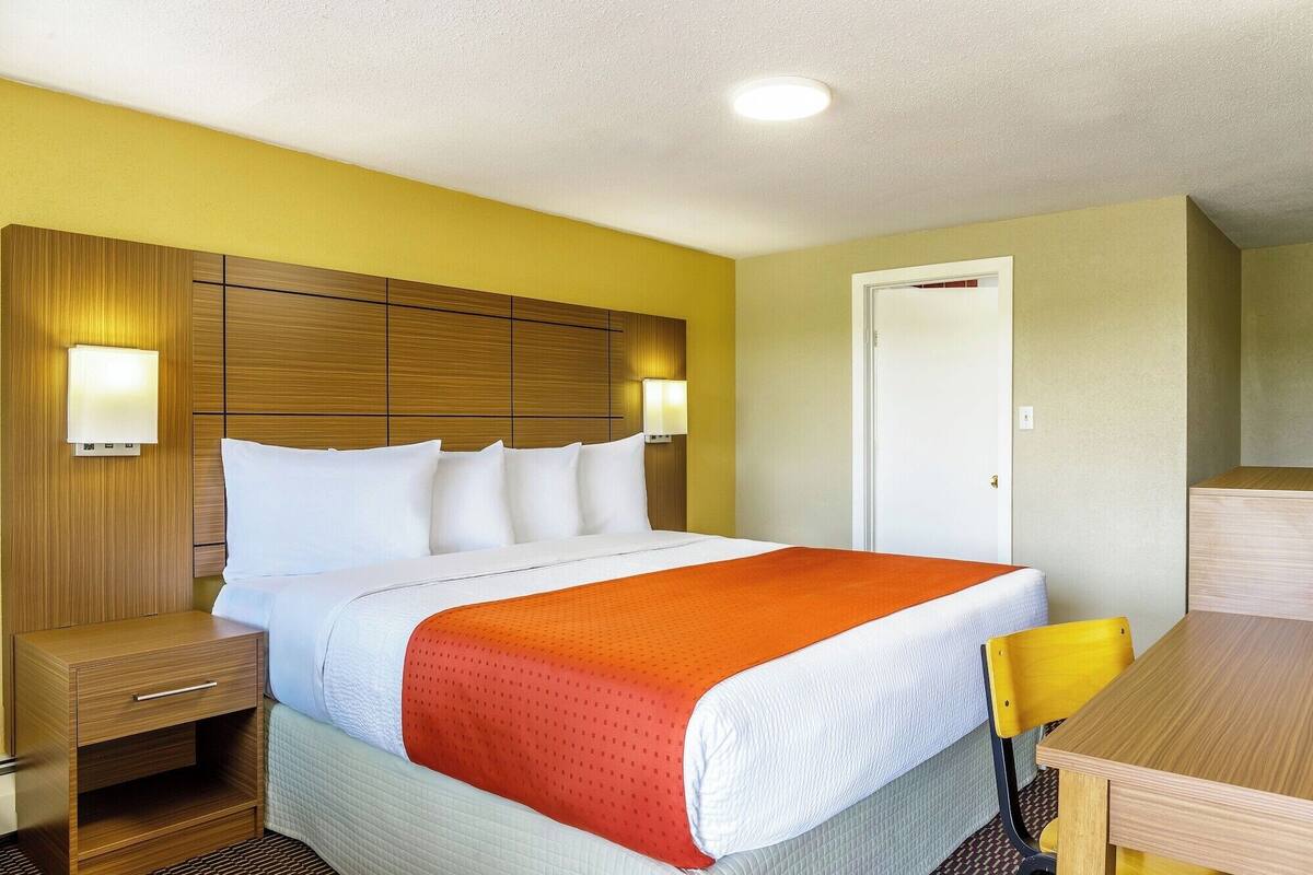 Una habitación de hotel con cama, mesitas de noche, escritorio y una silla.