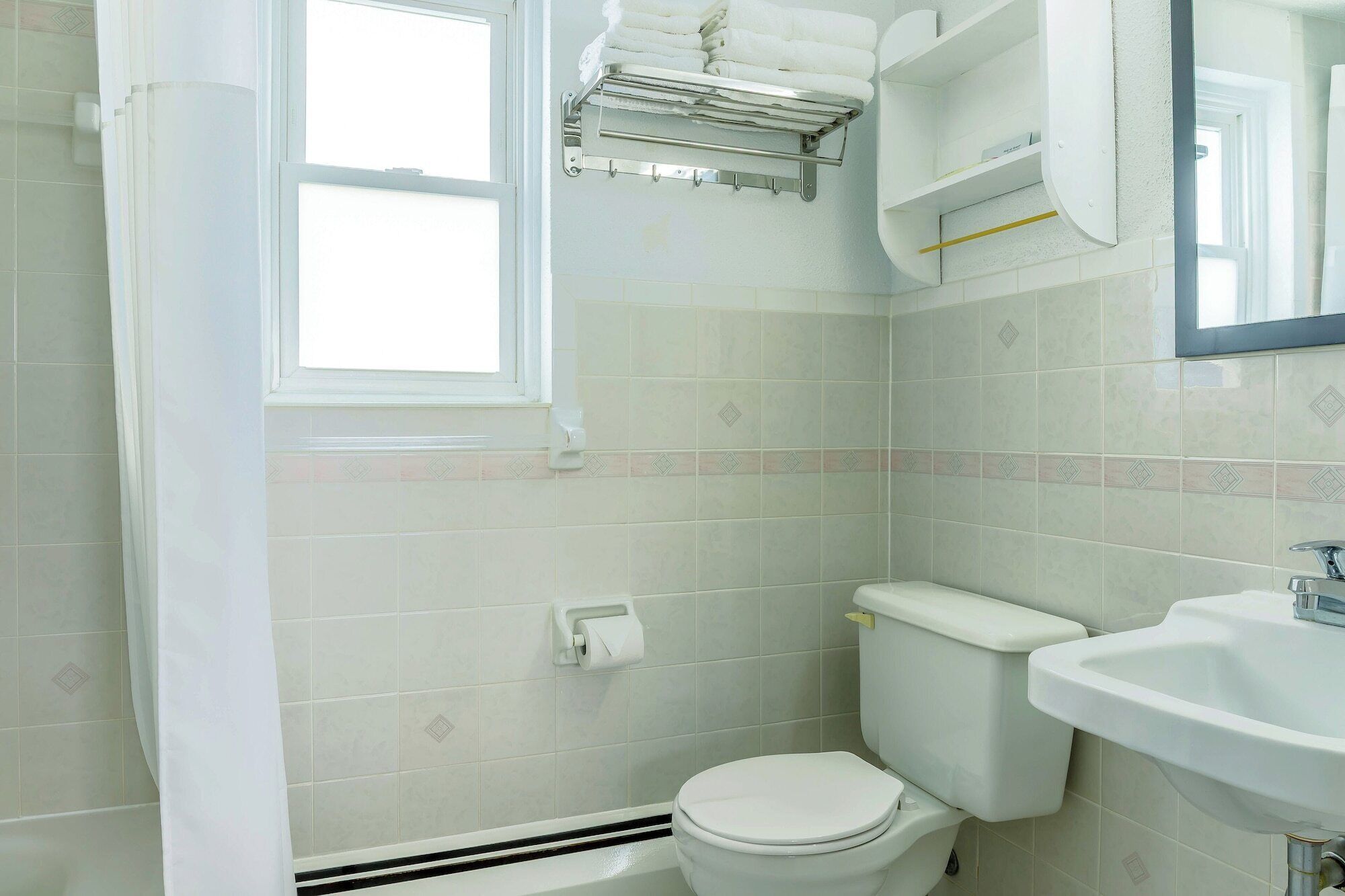 Un baño con inodoro, lavabo y toallero.