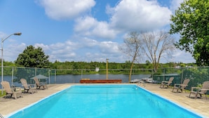 A swimming pool with lounge chairs and a view of a lake. - Motel 6 Campbellford, ON (Trent Hills)