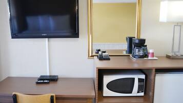A hotel room with a TV, a coffee maker, a microwave, a desk, and a chair.