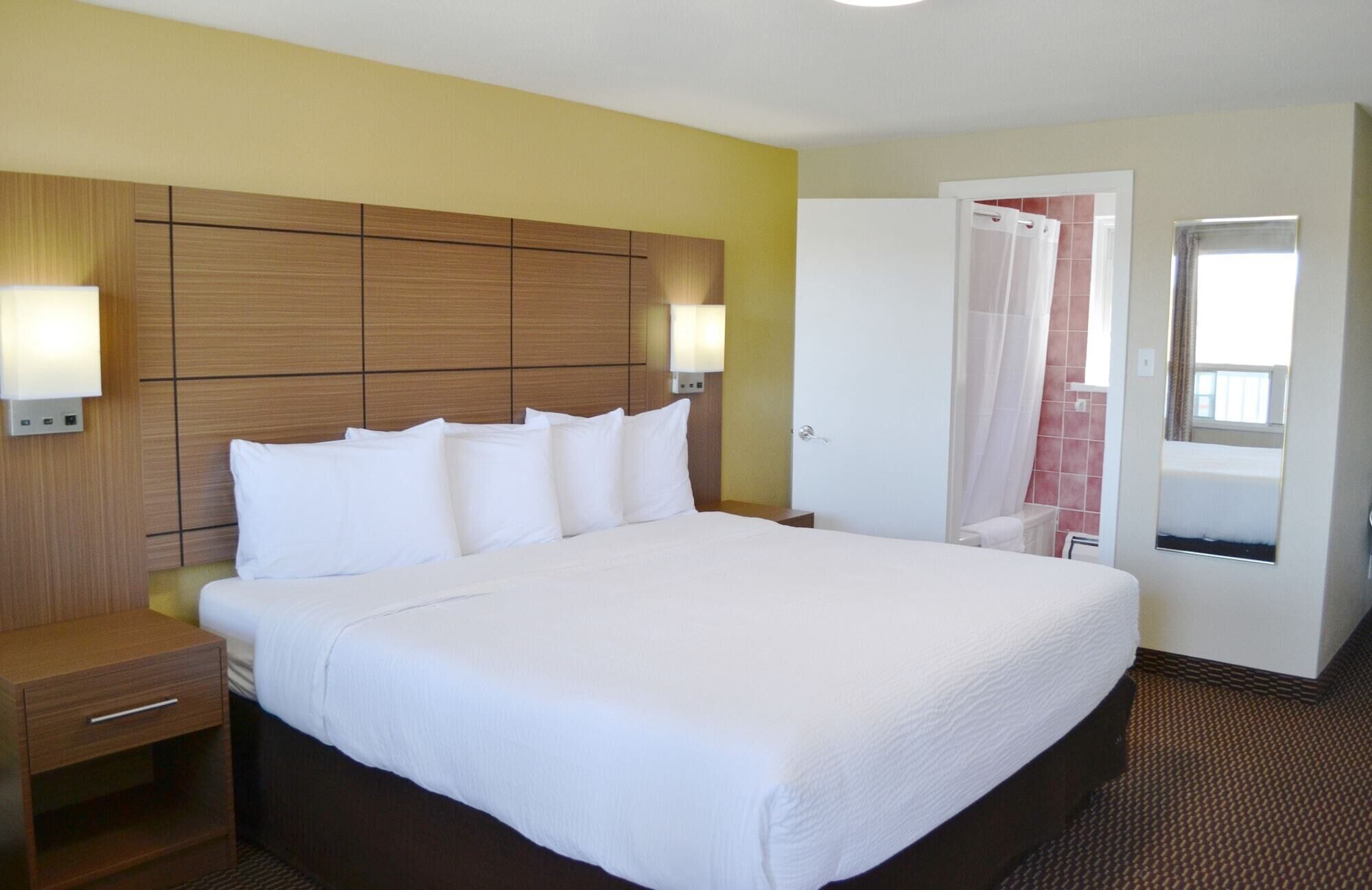 A hotel room with a large bed, a wooden headboard, a bedside table, and a wardrobe.