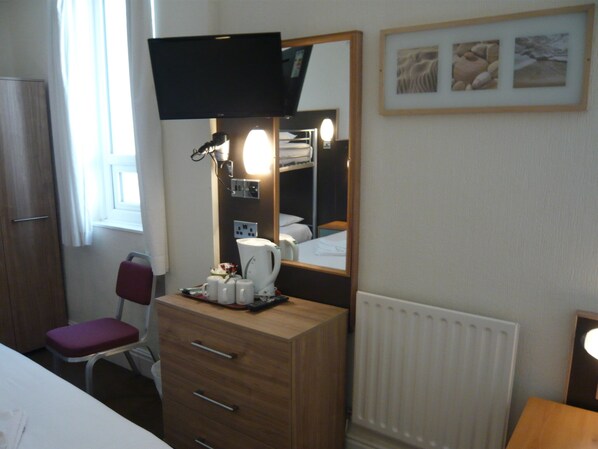 A hotel room with a bed, a dresser, a television, a mirror, and a window.