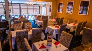 A restaurant with multiple tables and chairs, each with a menu sign. - Dutchman Hotel (Blackpool)
