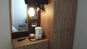 A wooden dresser with a mirror, a television mounted above it, and a coffee maker on the counter. - Dutchman Hotel (Blackpool)