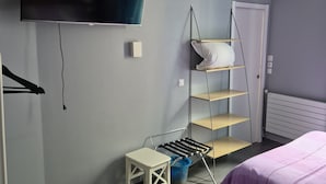A bedroom with a bed, a TV, a shelf, and a small table. - Hôtel Le Carrosse (Paris)