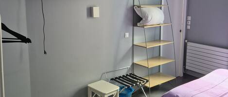 A bedroom with a bed, a TV, a shelf, and a small table.