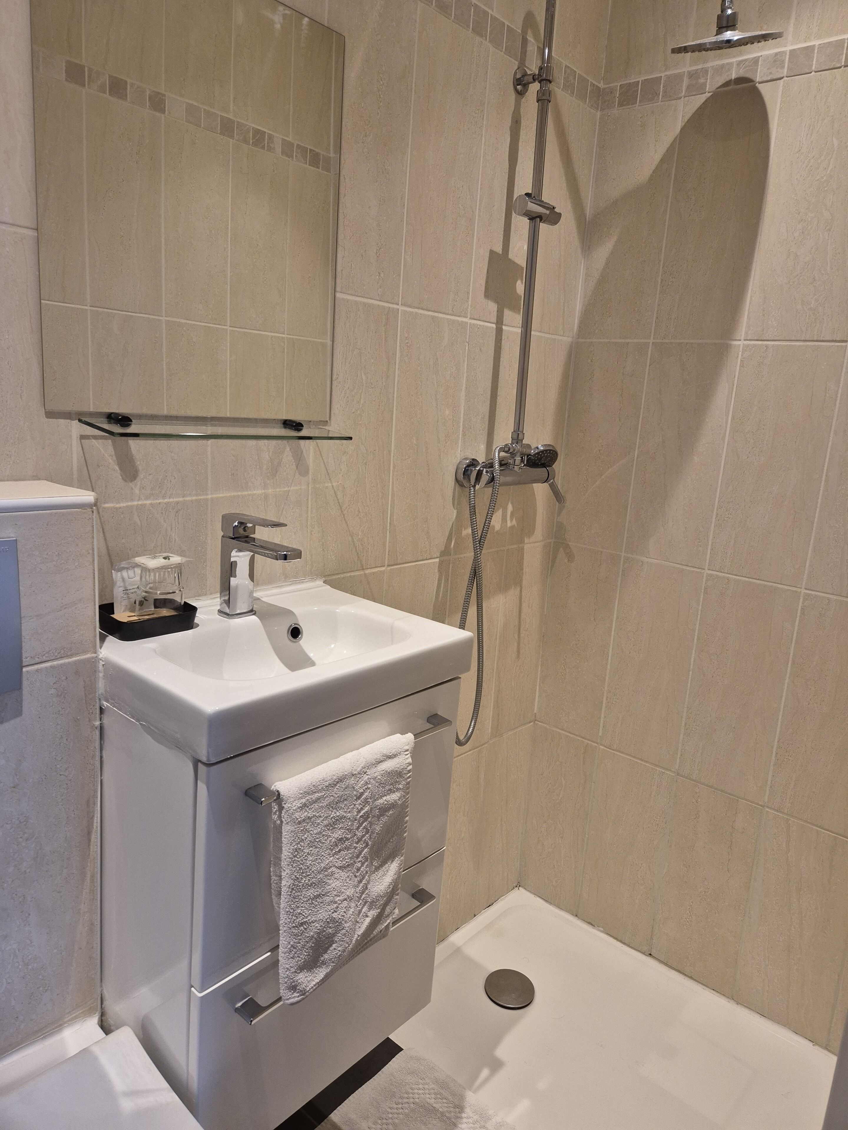 Un baño moderno con lavamanos, espejo y ducha blancos.
