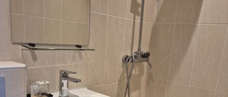Un baño moderno con lavamanos, espejo y ducha blancos.