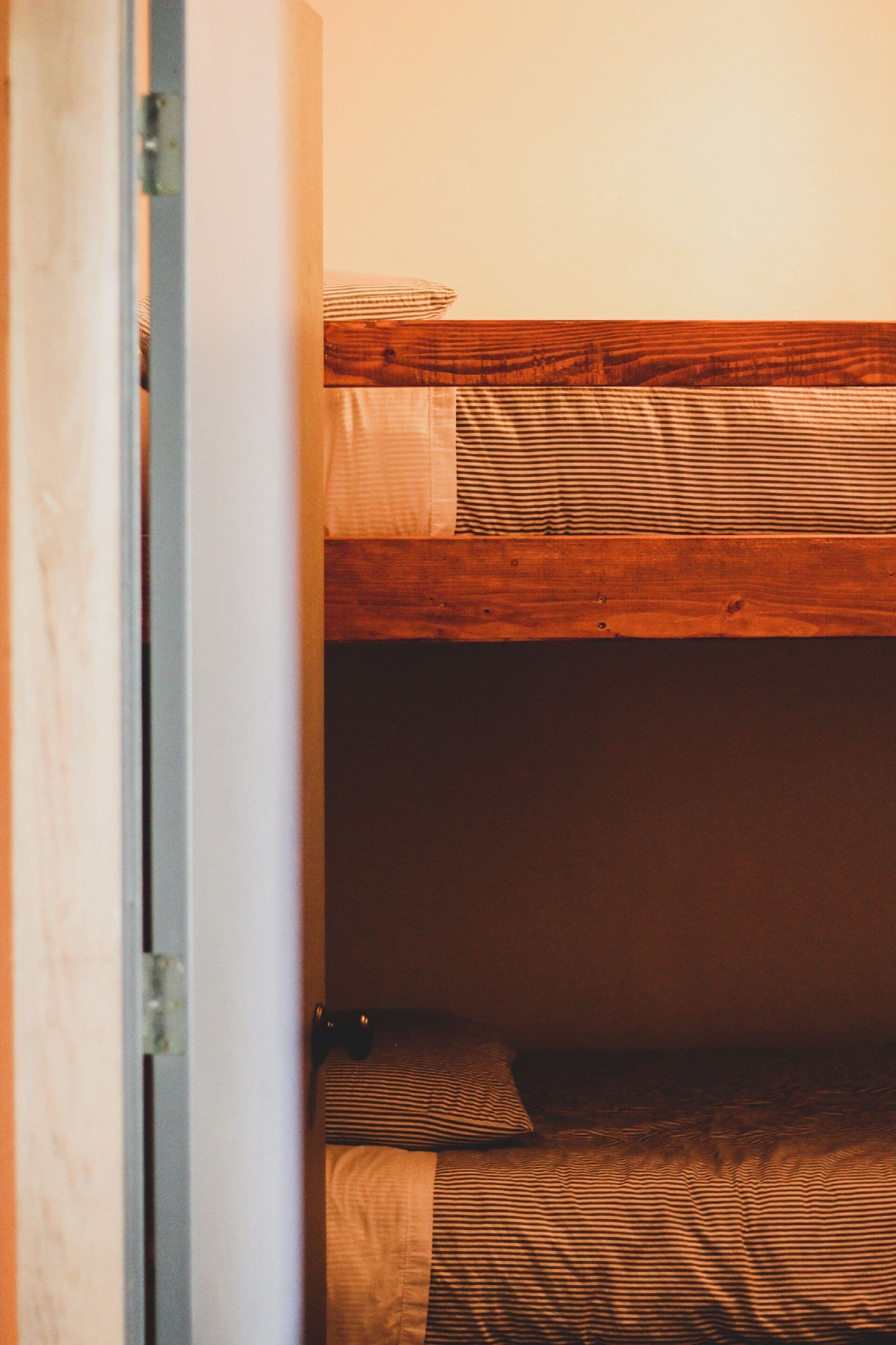 Un lit superposé avec une literie à rayures et une tête de lit en bois.