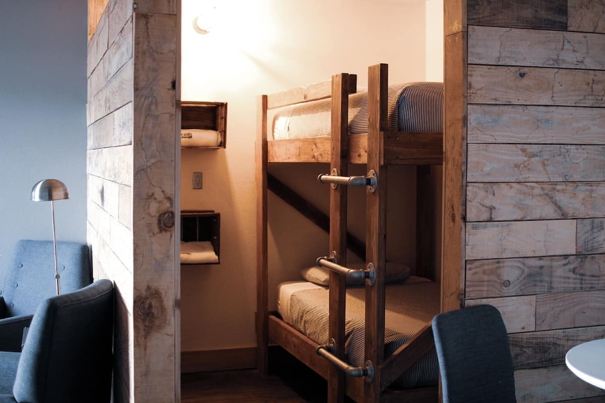 A compact room with a bunk bed, a small desk, and a chair.