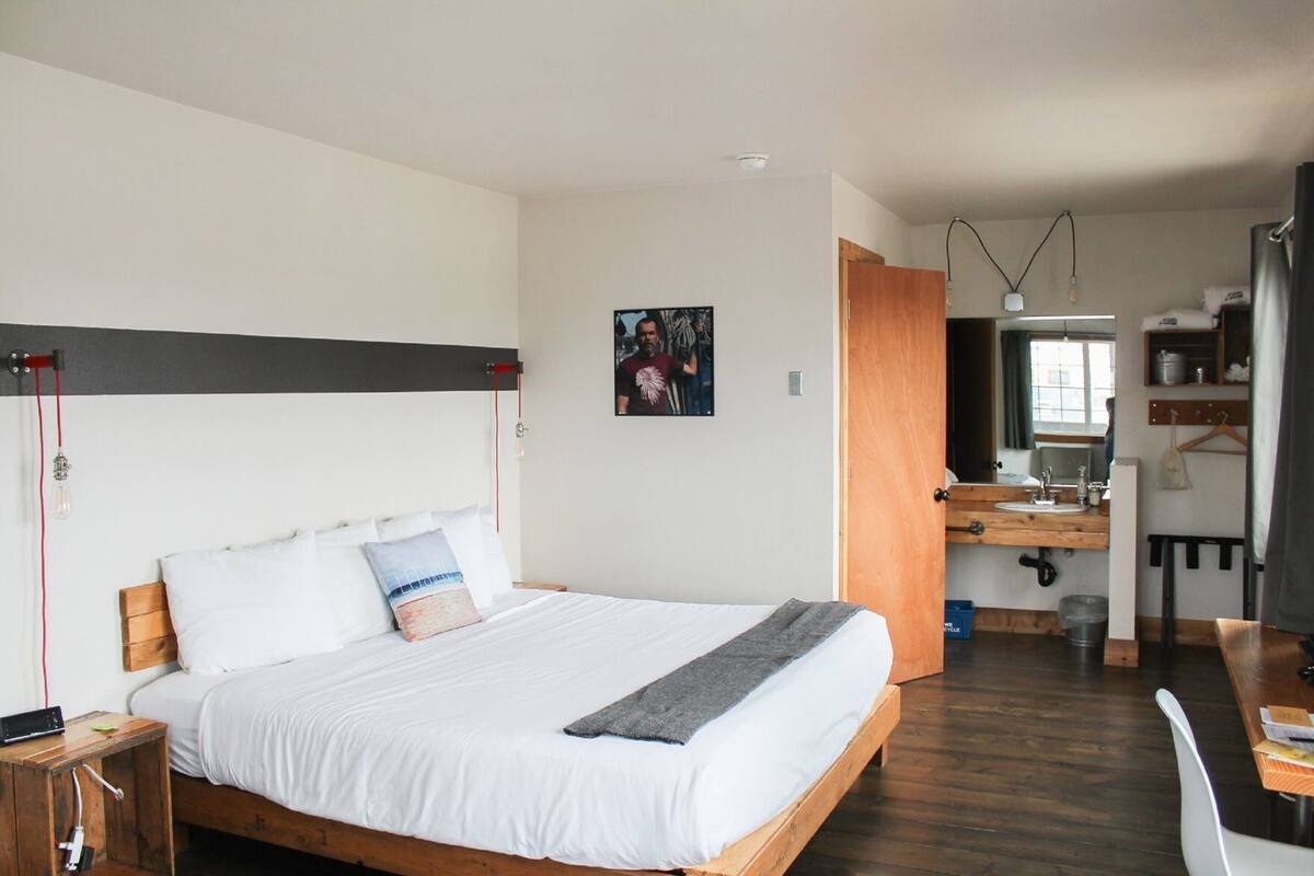 A bedroom with a bed, bedside table, and a small desk with a chair.
