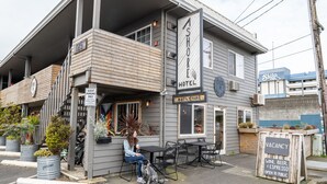 A hotel with a balcony, outdoor seating, and a sign indicating guest parking. - Ashore Hotel (Seaside)