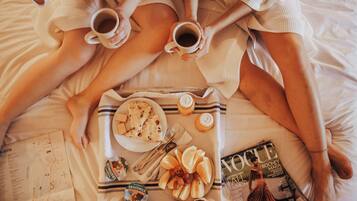 A bed with a tray of breakfast items, a magazine, and a map.
