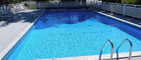 Ein rechteckiger Pool mit einer 3 Fuß tiefen Markierung, umgeben von einer weißen Terrasse und einem weißen Zaun.