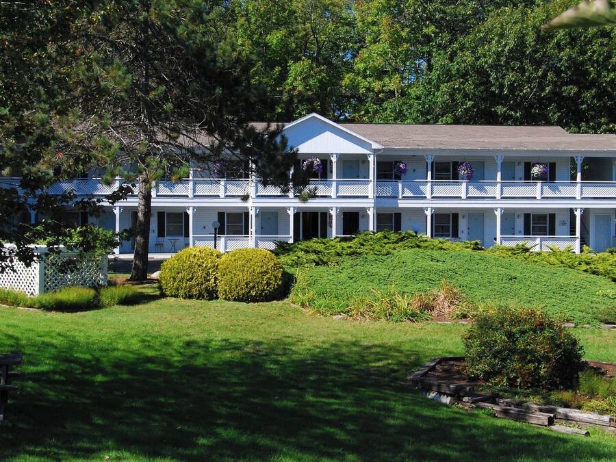 A two-story building with a white exterior, multiple balconies, and a well-maintained garden.