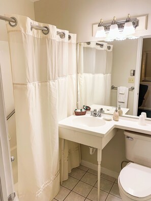 A bathroom with a white sink, mirror, and shower curtain.