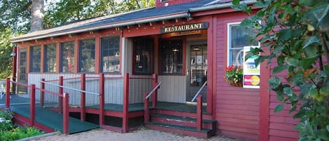 Edifici de fusta vermell amb un rètol que diu "RESTAURANT" i una mostra d'opcions de pagament que inclou Visa i Mastercard.