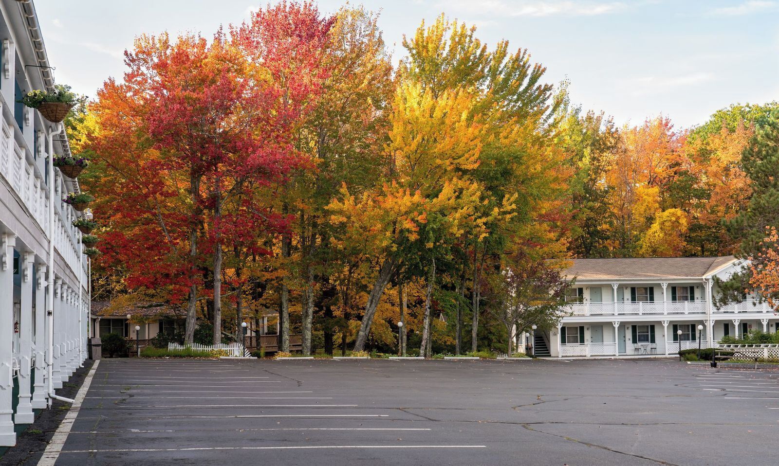 A parking lot with a row of white buildings, one with a balcony.