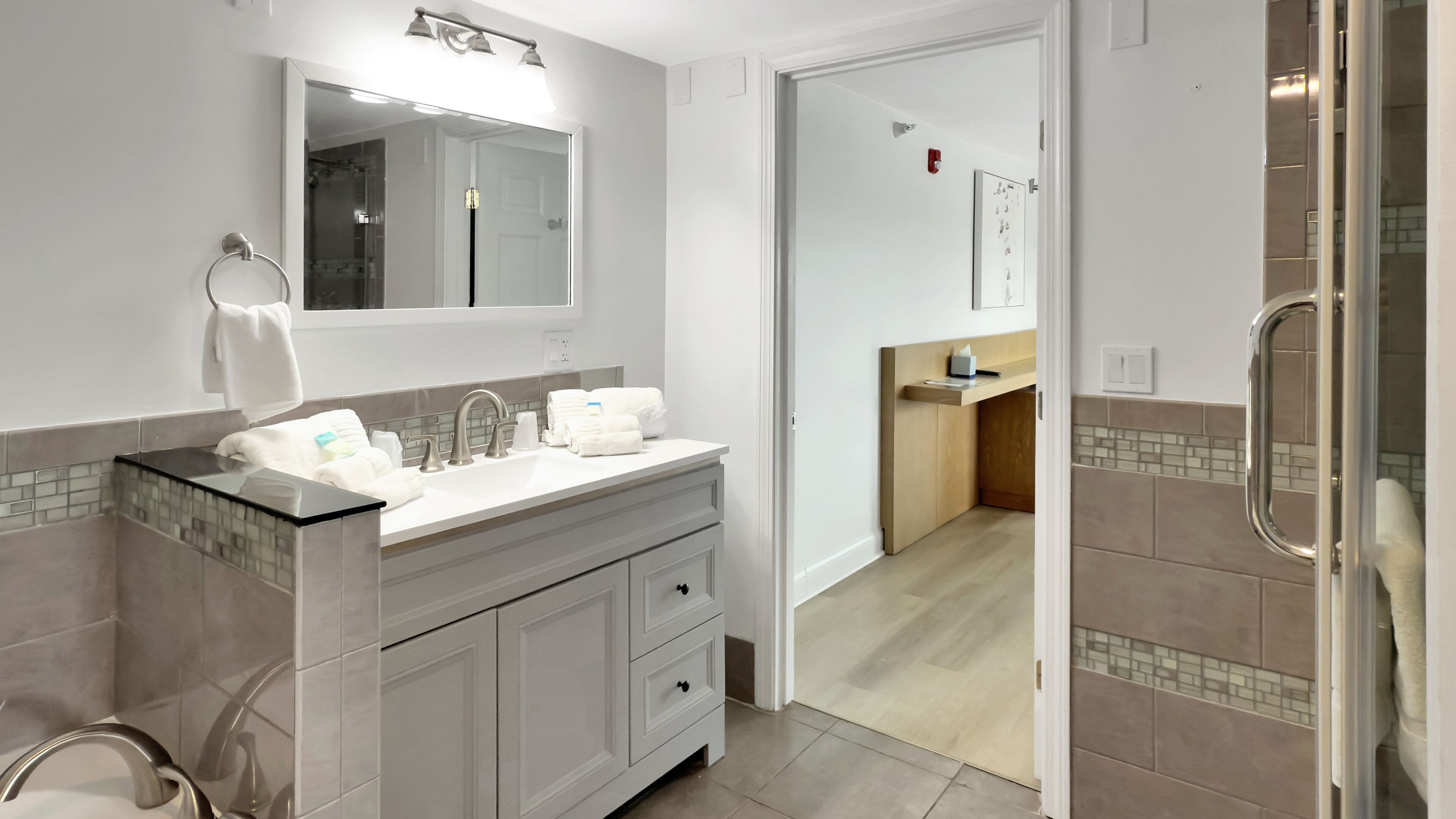 Un baño moderno con tocador doble, espejo y zona de ducha.