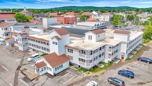 A hotel with a central tower, multiple stories, and a parking lot with several cars. - Harborline Hotel (Rockland)
