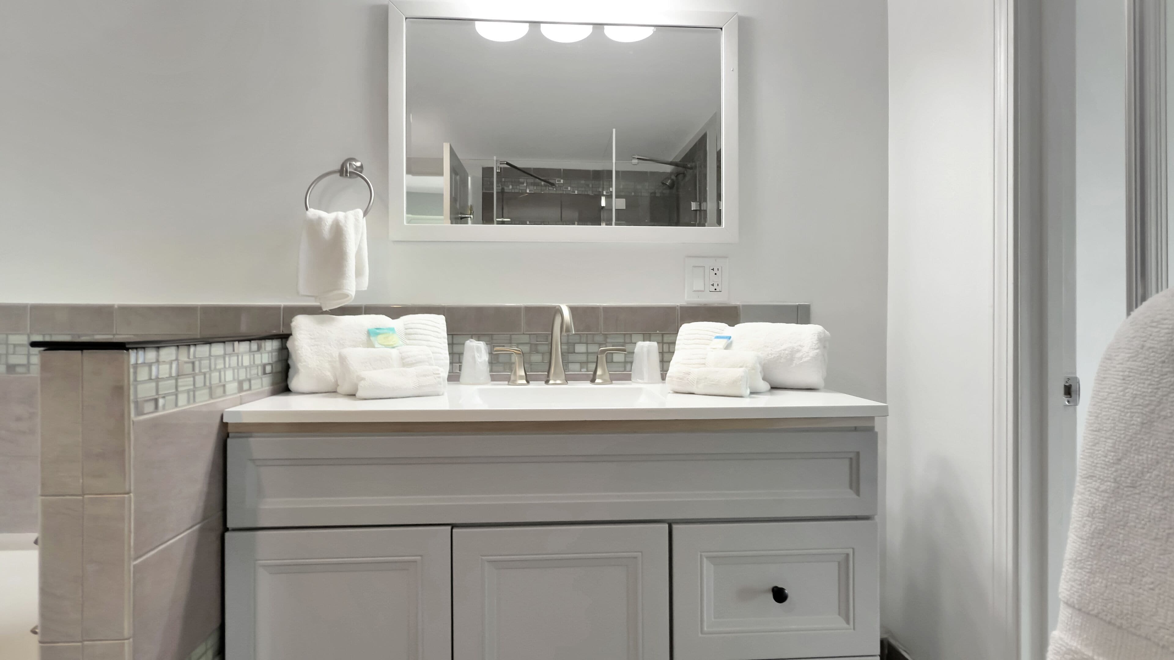 A bathroom with a double sink vanity, a towel ring, and a mirror above the sink.